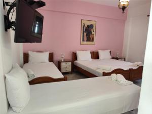 two beds in a room with pink walls and a tv at Grivas Apartments in Sivota