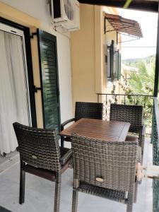 a wooden table and chairs on a balcony at Grivas Apartments in Sivota