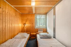 two beds in a room with wooden walls and a window at Bungalow 30 - Kimbucht in Reichendorf