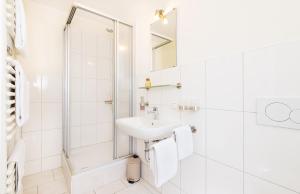 a white bathroom with a shower and a sink at Pension Altes Backhaus in Herzogenaurach