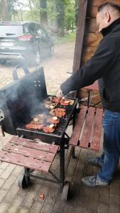 a man is cooking food on a grill at Palac Kursko Agroturystik in Kursko