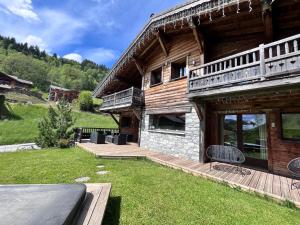 a log cabin with a deck and a patio at Chalet Virolet in Les Gets