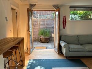 a living room with a couch and an open door at Self-contained studio with patio in Ware