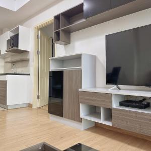 a living room with a large television and a kitchen at Supalai Mare Pattaya & City Center in Pattaya South