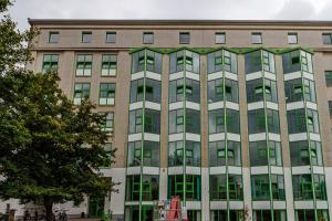 een groot bakstenen gebouw met groene en witte ramen bij Kapselhotel nähe Hauptbahnhof Halle-Saale in Halle an der Saale