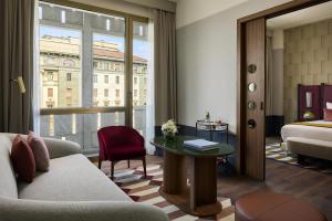 a hotel room with a couch and a bed and a window at Tivoli President Milano Hotel in Milan