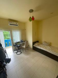 a bedroom with a bed and a table and a desk at Sweden Inn Hostel Chalong in Ban Klang