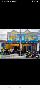 a blue and yellow building with cars parked in front of it at Sweden Inn Hostel Chalong in Ban Klang +22 photos