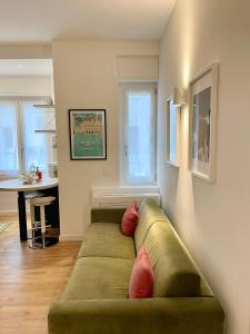 una sala de estar con un sofá verde con almohadas rojas en Plinio 72 Apartment, en Milán