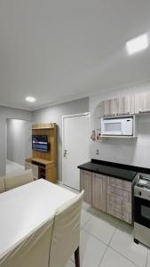 una cucina con tavolo bianco e forno a microonde di Apartamento Residencial Ana Capri a Capão da Canoa