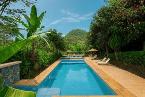 a swimming pool with two chairs and a table at Hostería los Cedros de Mindo in Mindo