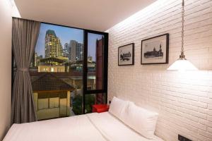 a bedroom with a white bed and a large window at Sleep Box Sukhumvit 22 in Bangkok +33 photos