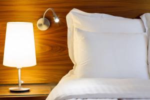 サンタクルス・デ・テネリフェにあるEurostars Atlántidaのベッド(白い枕、ランプ付)