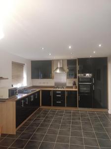 eine Küche mit schwarzen Schränken und schwarzen Geräten in der Unterkunft Holiday retreat next to nature in Corby and Weldon + 28 Fotos