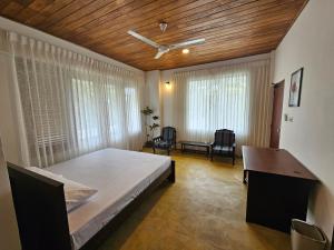 a bedroom with a bed and a desk and windows at Town Hill in Kegalle