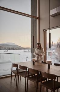 a woman standing in a room with a large window at Joiku Luxury Lakeview Chalet in Kolari