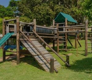 a wooden playground with a slide in a park at Banana Beach Club C5 in Port Shepstone