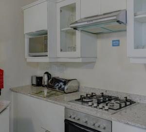 a kitchen with white cabinets and a stove top oven at Banana Beach Club C5 in Port Shepstone