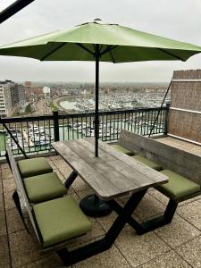 a wooden table with chairs and an umbrella on a balcony at Penthouse Vakantielust in Blankenberge