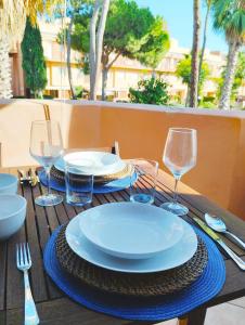 a wooden table with plates and wine glasses on it at Apartamento luminoso y acogedor en Residencial Altavista Islantilla in Islantilla