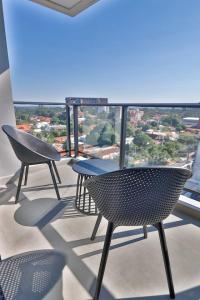 three chairs and tables on a balcony with a view at Cozy apartment near Shopping del Sol in Asuncion