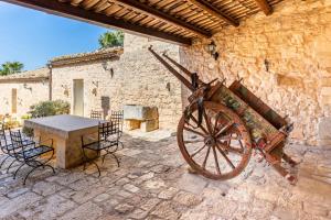 a stone building with a table and an old wheel at Agriturismo Al Casale in Donnafugata