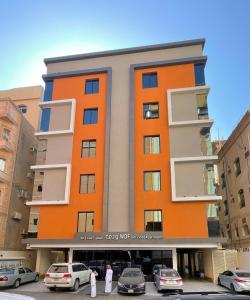 an orange building with cars parked in a parking lot at شقق ودف للشقق المخدومة Wdf Serviced Apartments in Jeddah