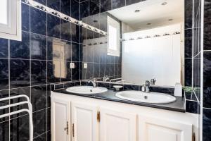 a black tiled bathroom with two sinks and a mirror at La Maison Du Bonheur in Fresnay-en-Retz +15 photos