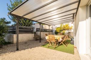 a pergola on a patio with a table and chairs at La Maison Du Bonheur in Fresnay-en-Retz