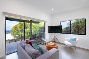 a living room with a couch and a tv and windows at Luxe on Seacrest in Encounter Bay