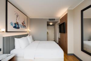 a hotel room with a white bed and a mirror at Radisson Blu Hotel & Spa, Daugava Riga in Rīga