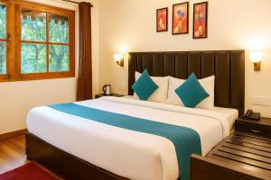 a bedroom with a large bed with blue pillows at Heyan Cedar Woods Nainital, 5 Mins walk from Mall Road in Nainital
