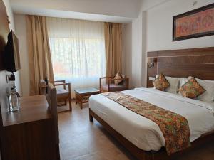 a hotel room with a large bed and a desk at Amritara Ramila Kutir in Ayodhya