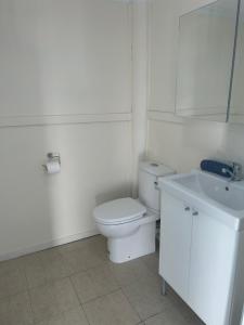 a white bathroom with a toilet and a sink at Picturesque Lakeside Getaway: Views, Beach, Park in Loch Sport +58 photos