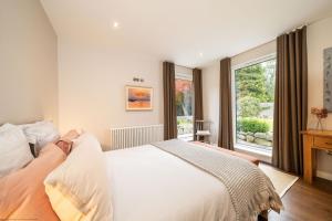 a bedroom with a white bed and a window at Stables Cottage in Dunira