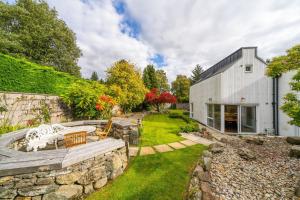 a garden with a stone wall and a building at Stables Cottage in Dunira