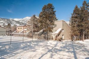 a building with a fence in the snow at RMR: Mountain Maple 4 Condo in The Aspens in Wilson