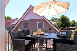 a hat sitting on a table on a balcony with an umbrella at FeWo Paluc in Wustrow