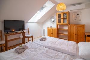 a bedroom with a large white bed and a flat screen tv at Summerhouse penzion Bavory in Bavory