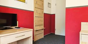 海利根达姆Mollibahnhof - Heiligendamm Mollibahnhof Heiligendamm EZ 03的配有电视和红色墙壁的客房