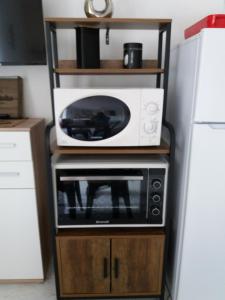 a microwave oven sitting on top of a wooden stand at Coup de cœur 3 étoiles terrasse parking Wifi à 70 m des thermes in Amélie-les-Bains-Palalda