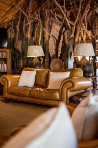 a leather couch in a living room with two lamps at Karongwe - Chisomo Safari Camp in Hoedspruit
