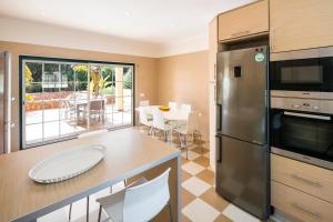 a kitchen with a stainless steel refrigerator and a table at Casa Dos Cedros in Carvoeiro