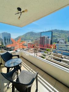 a balcony with chairs and a table and a view of a city at Liz Suites Providencia con balcón in Santiago