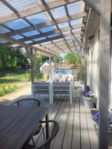 Una terraza de madera con un sofá debajo de una pérgola. en Domek na lipowym wzgórzu, en Długie
