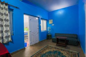 um quarto azul com um sofá e uma porta em Butterfly homestay em Ooty