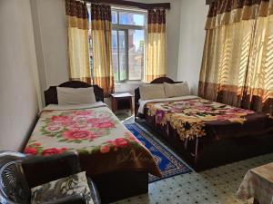 a room with two beds and a couch and a window at Elegant Guest House in Pokhara
