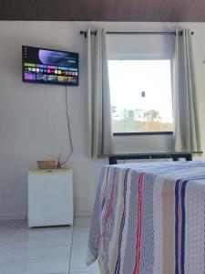 a bedroom with a bed and a television and a window at Chalé Bella Vista in Mulungu
