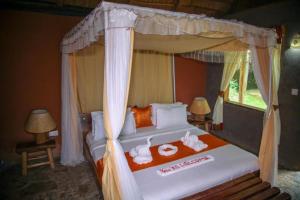 a bedroom with a bed with towels on it at Sharp Island Gorilla Lodge, Lake Bunyonyi in Kashasha