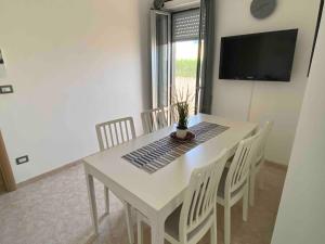 a white dining room table with white chairs and a television at Modern apartment - Salento Guest House in Monteroni di Lecce